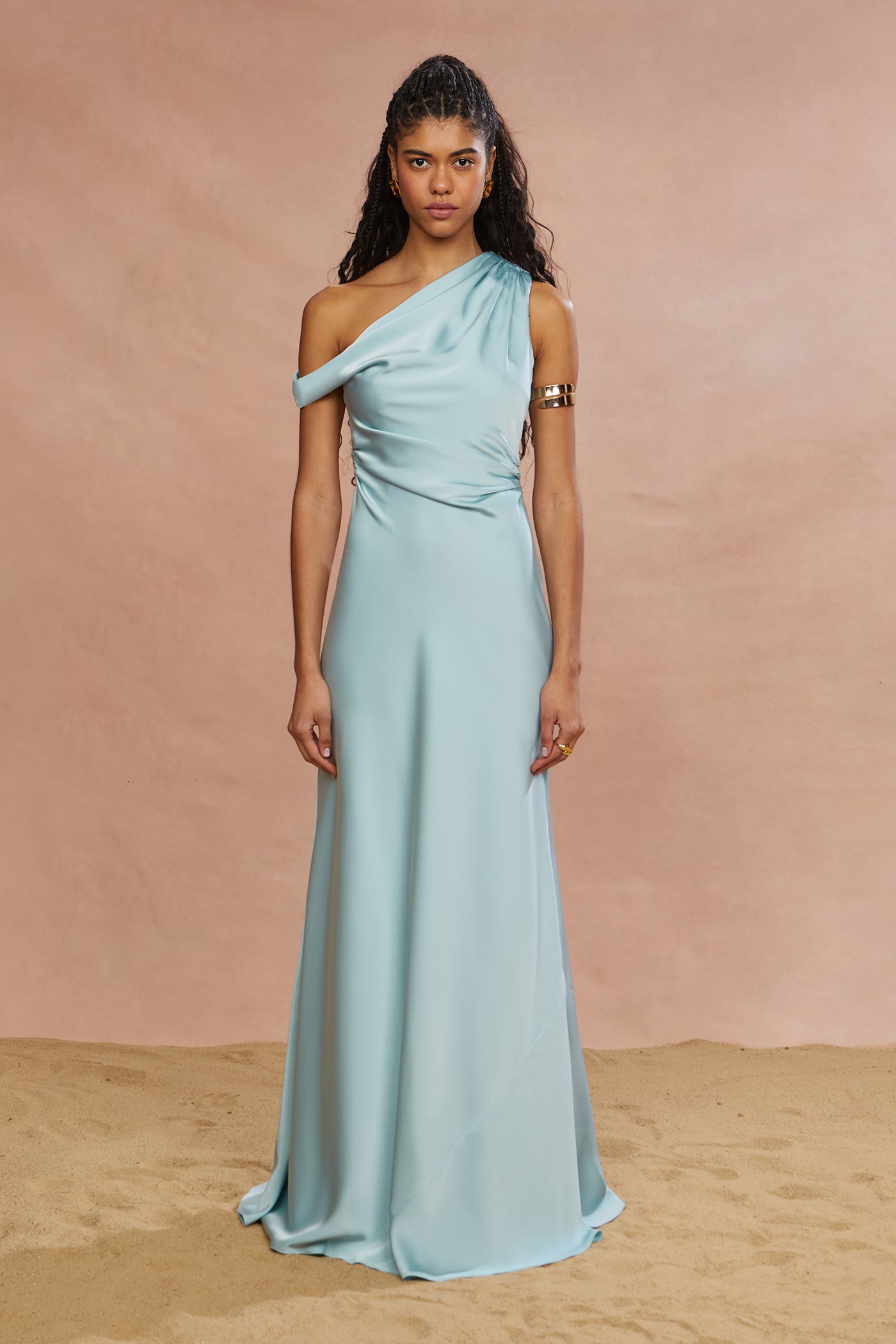 A woman wearing a blue gown with a one-shoulder neckline and a maxi length.
