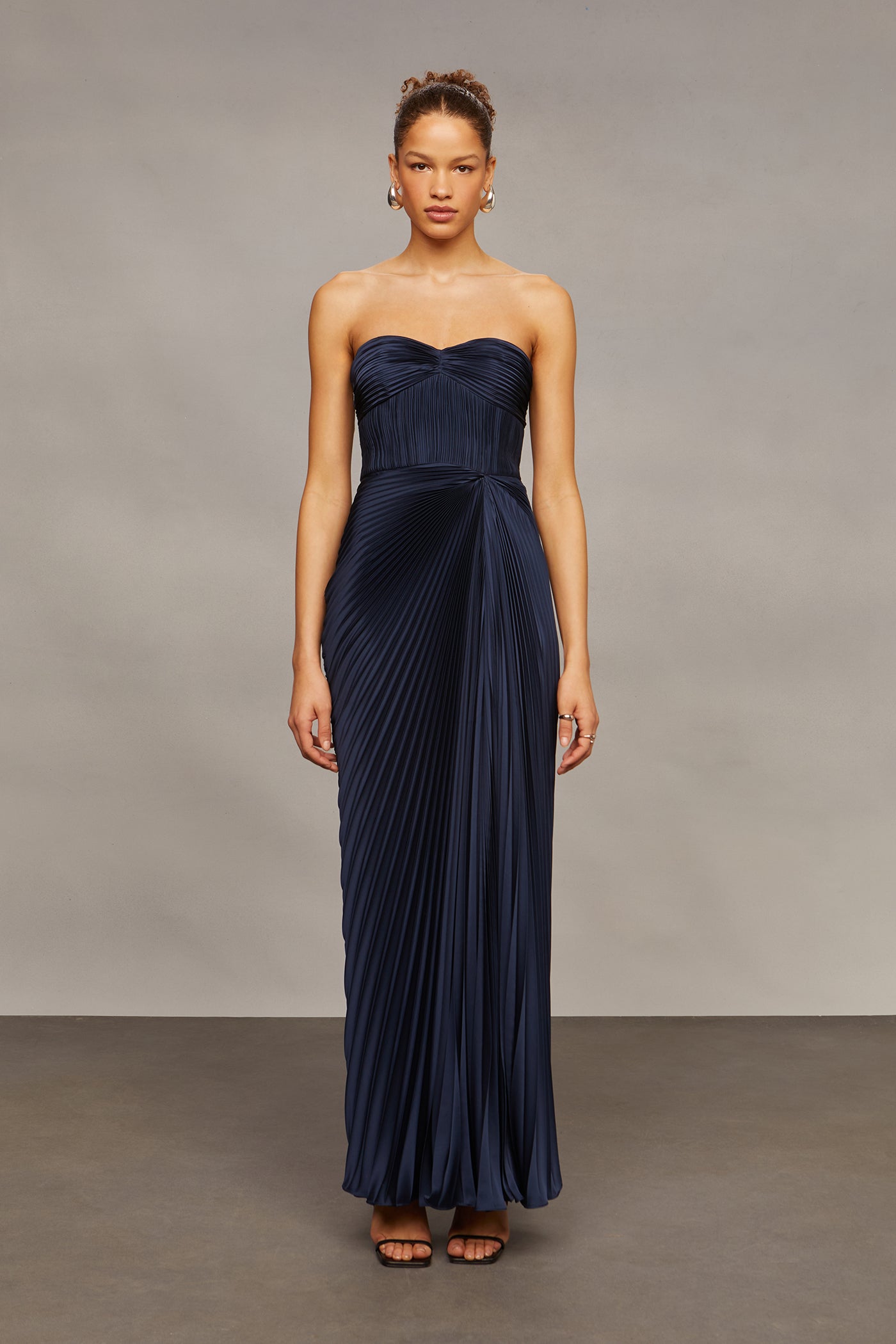 Woman wearing a strapless navy gown against a plain background