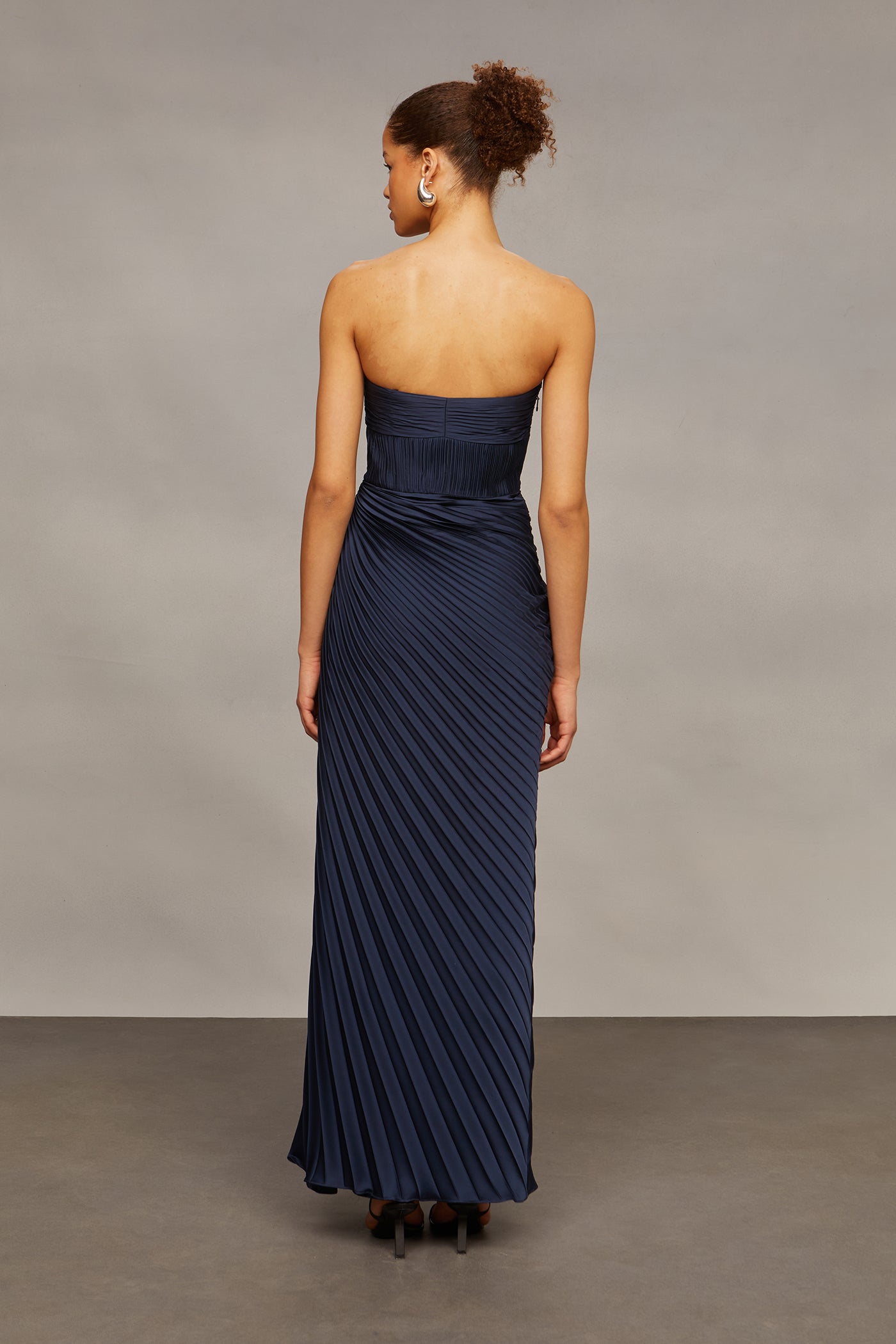 Woman wearing a strapless navy gown against a neutral background