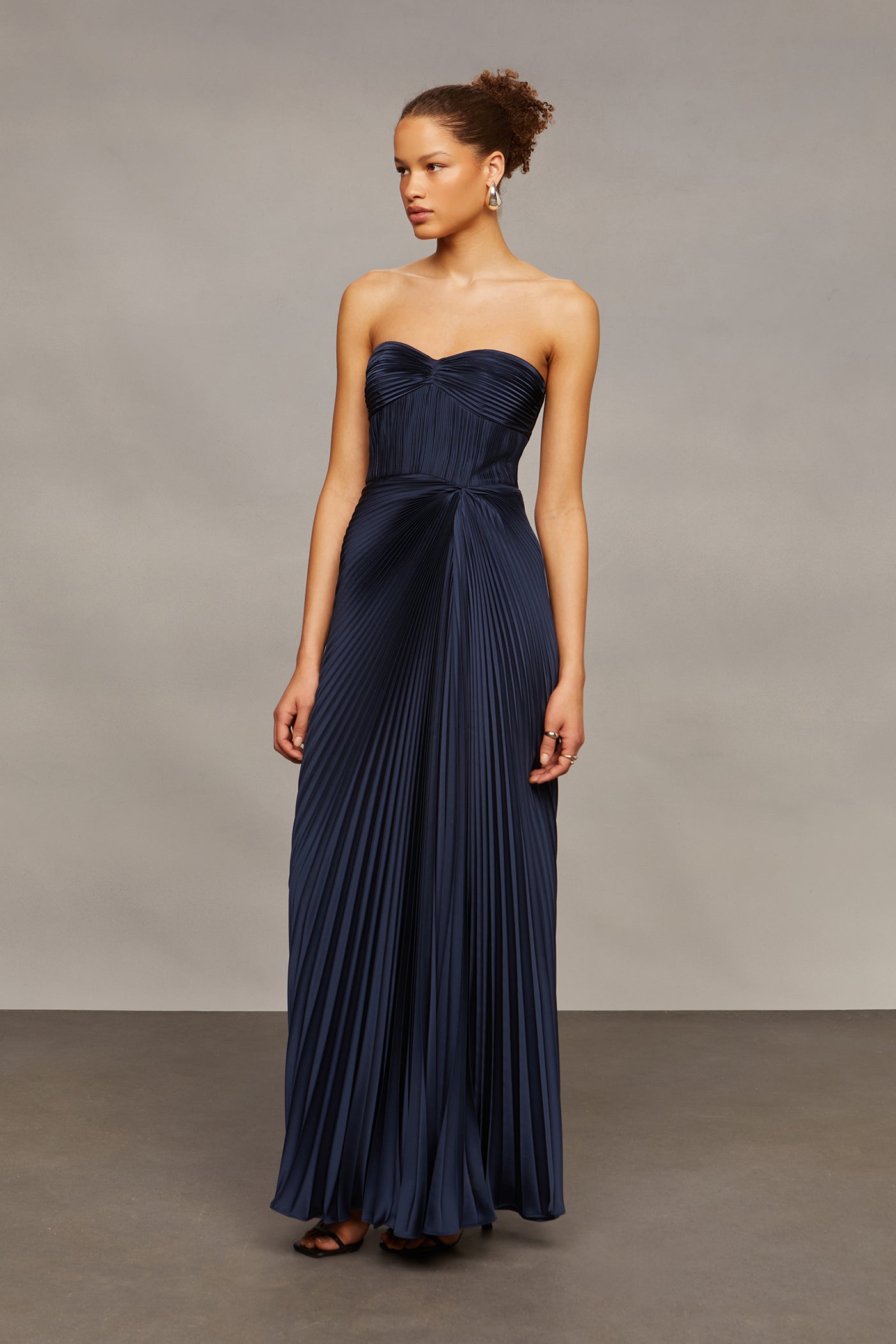 Woman wearing a strapless navy gown against a plain background