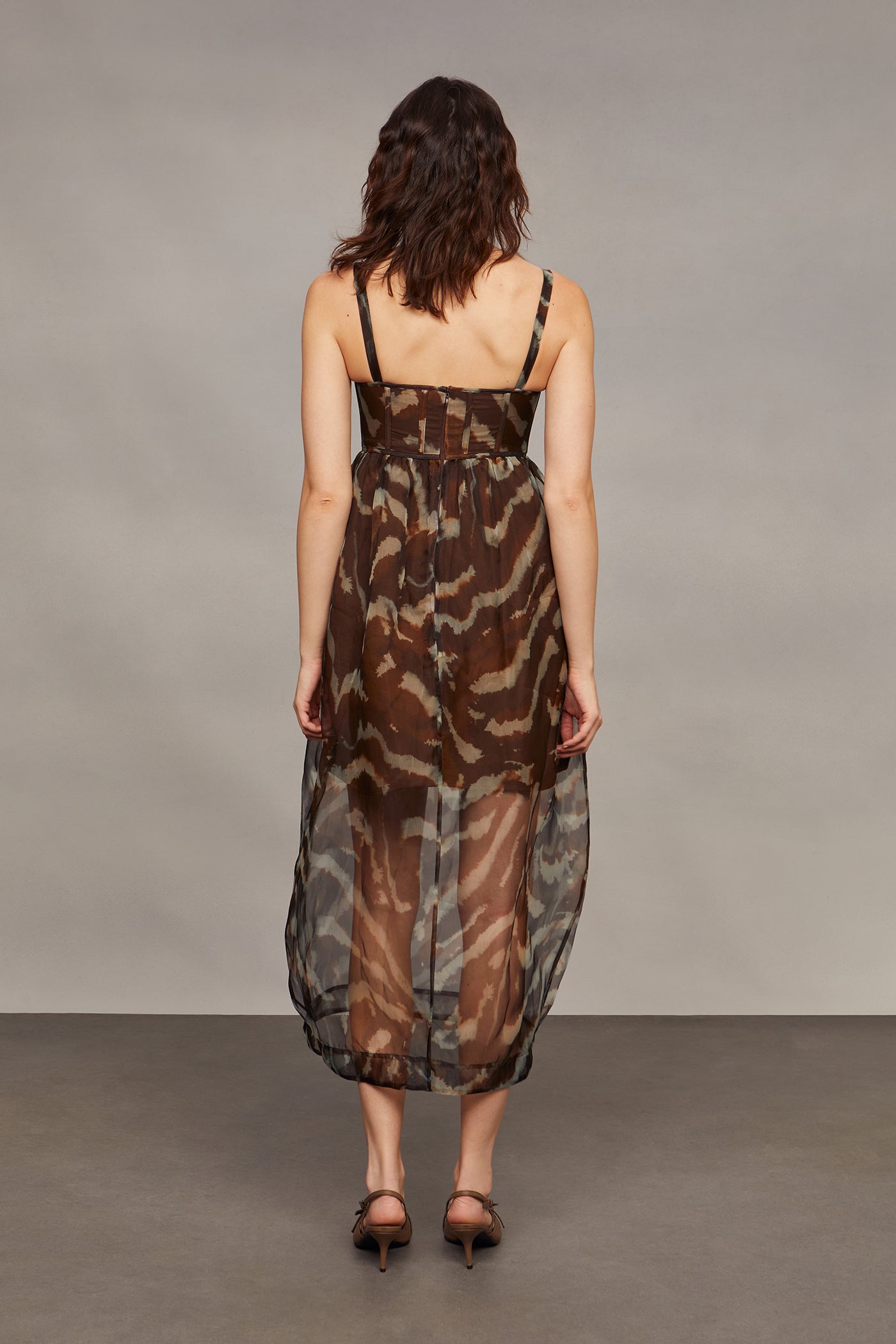 Woman wearing a camouflage dress against a plain background