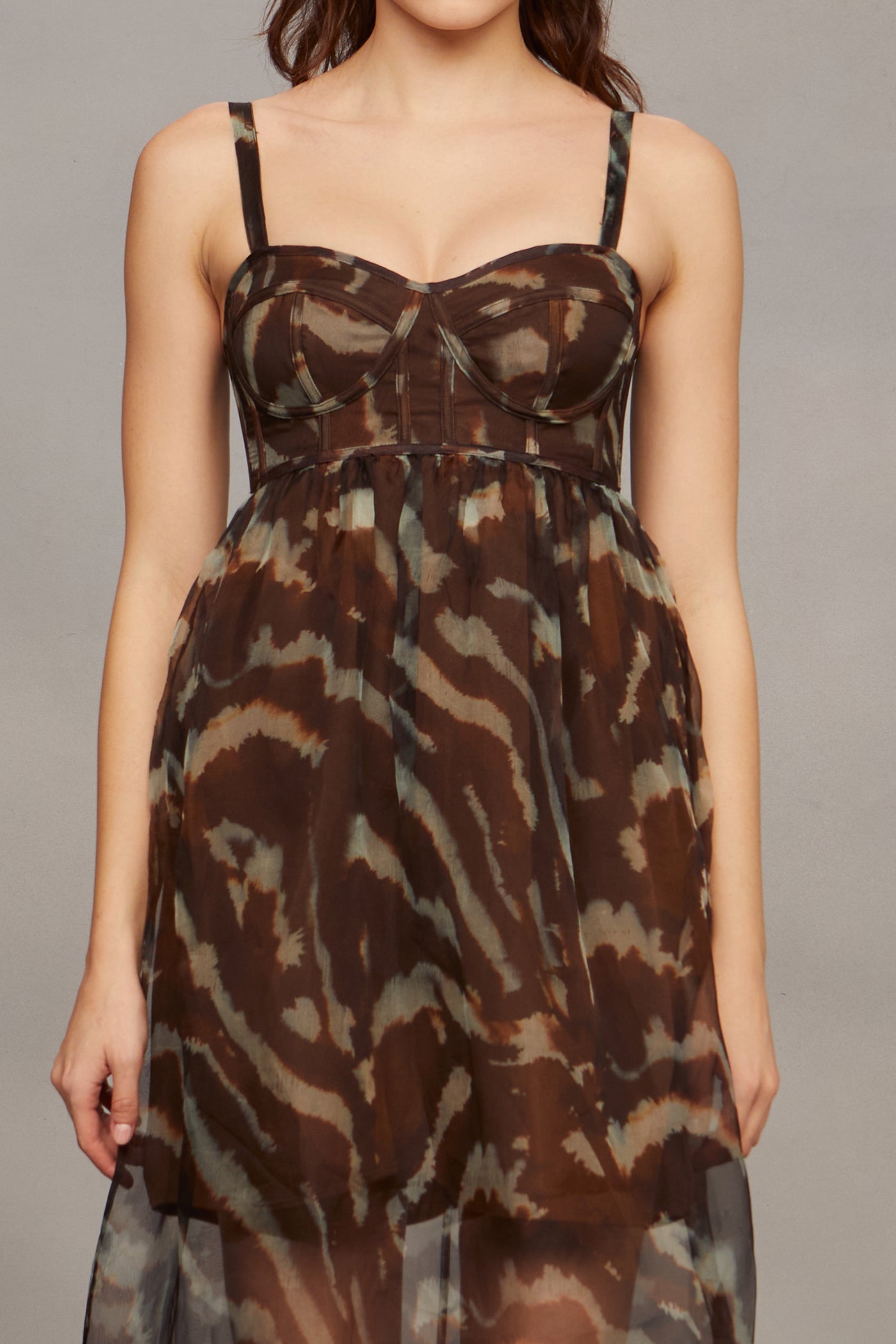 Woman wearing a brown and black patterned dress against a gray background