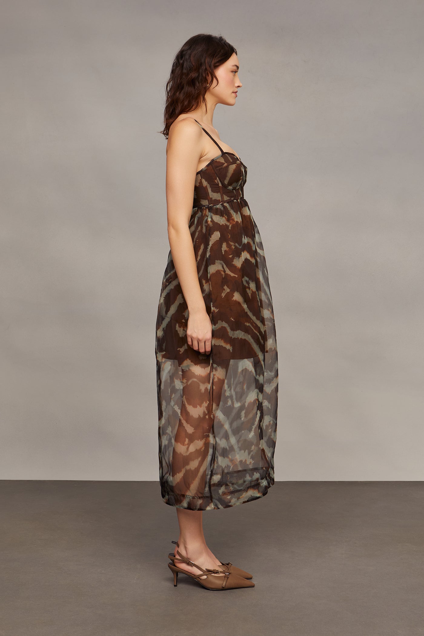Woman wearing a camouflage dress against a plain background