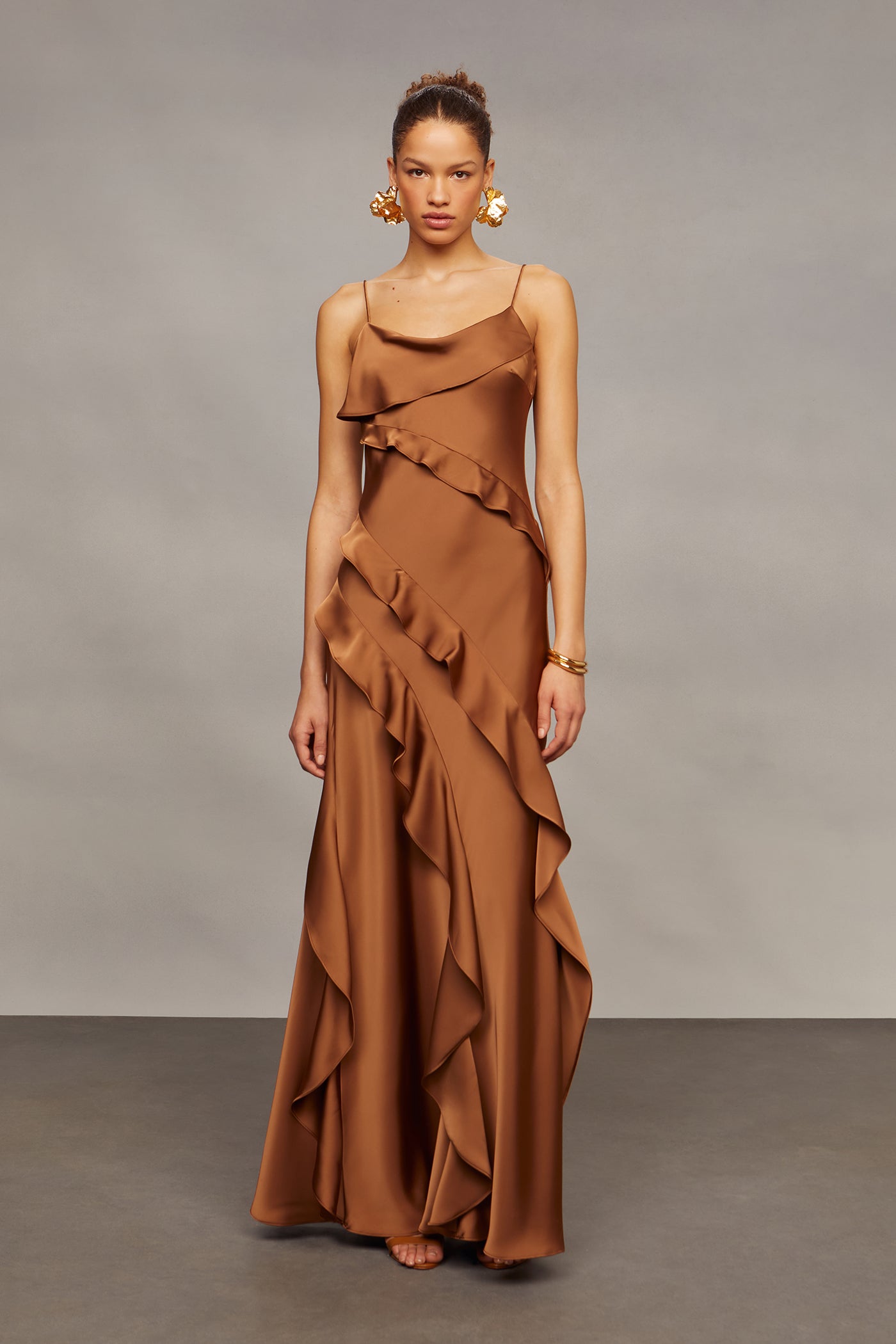 Woman wearing a brown evening gown with ruffled layers against a neutral background