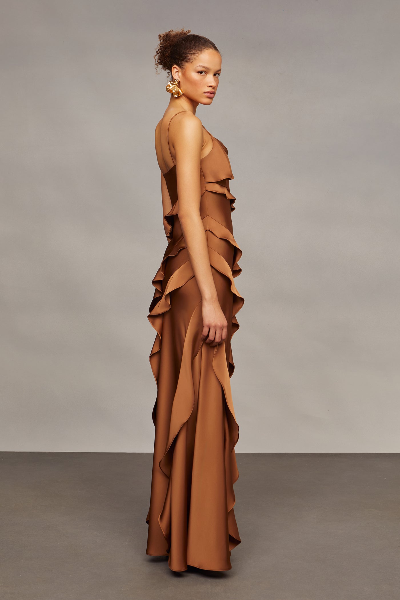 Woman wearing a brown ruffled dress against a plain background