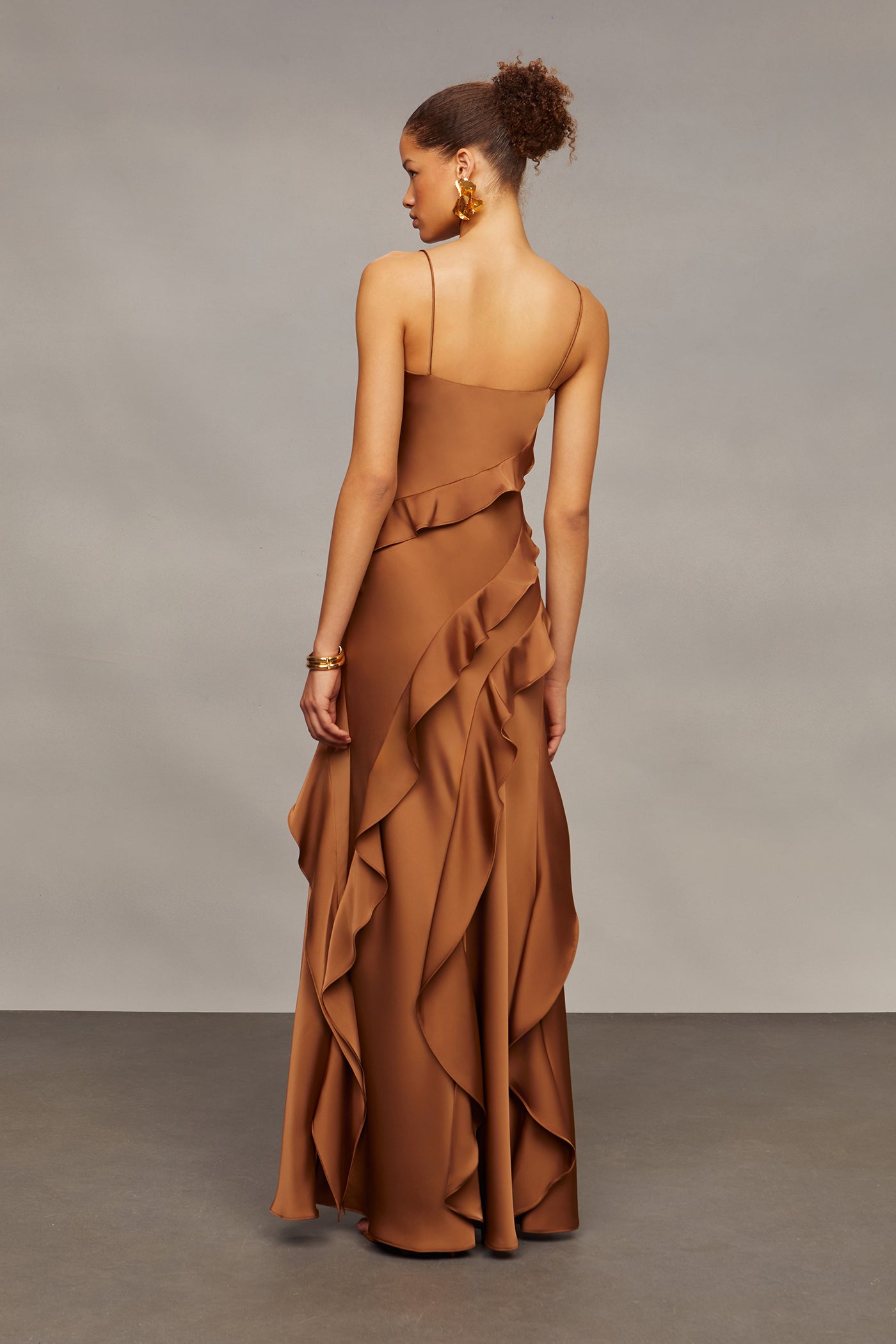 Woman wearing a brown ruffled dress against a plain background
