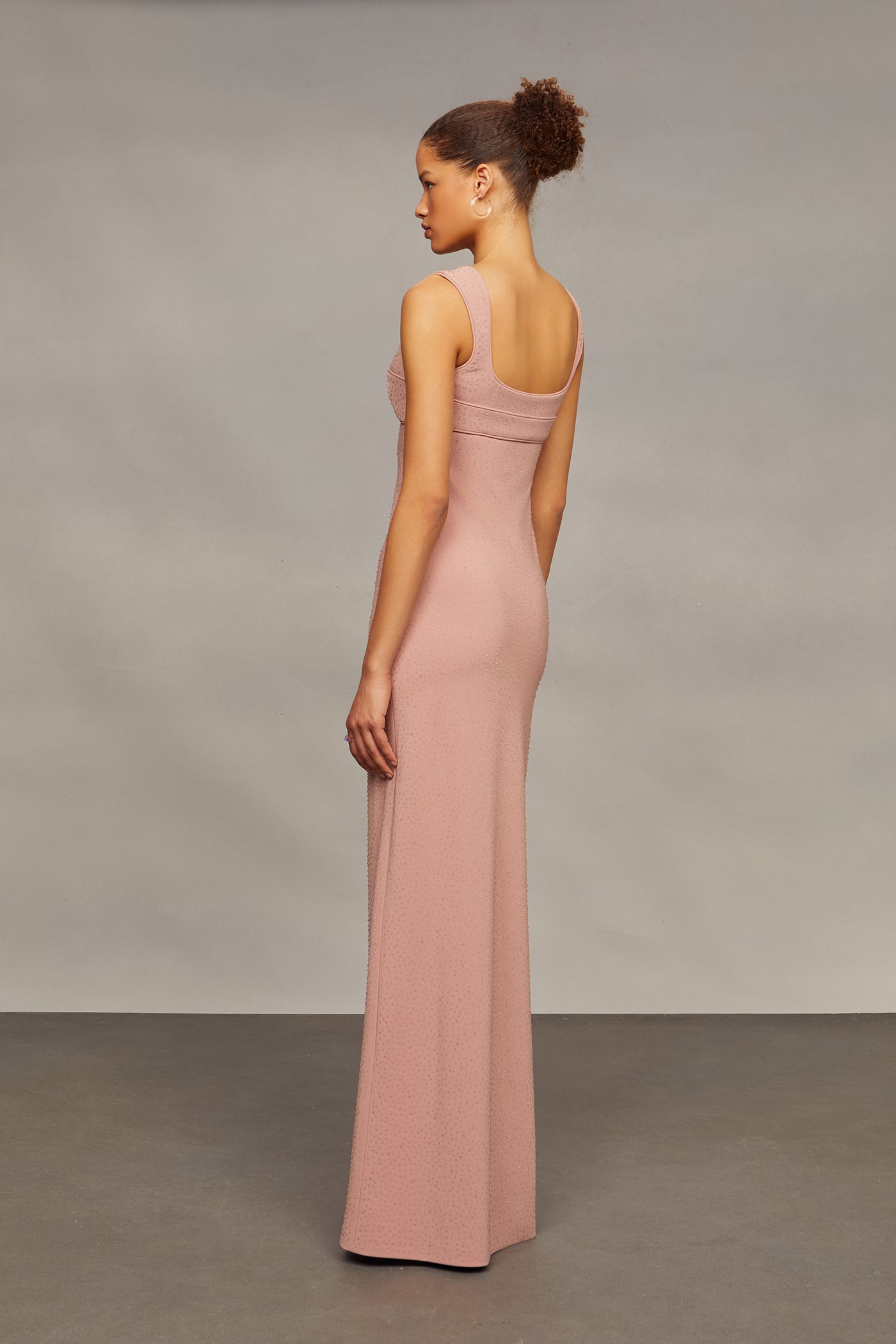Woman wearing a long pink dress against a neutral background