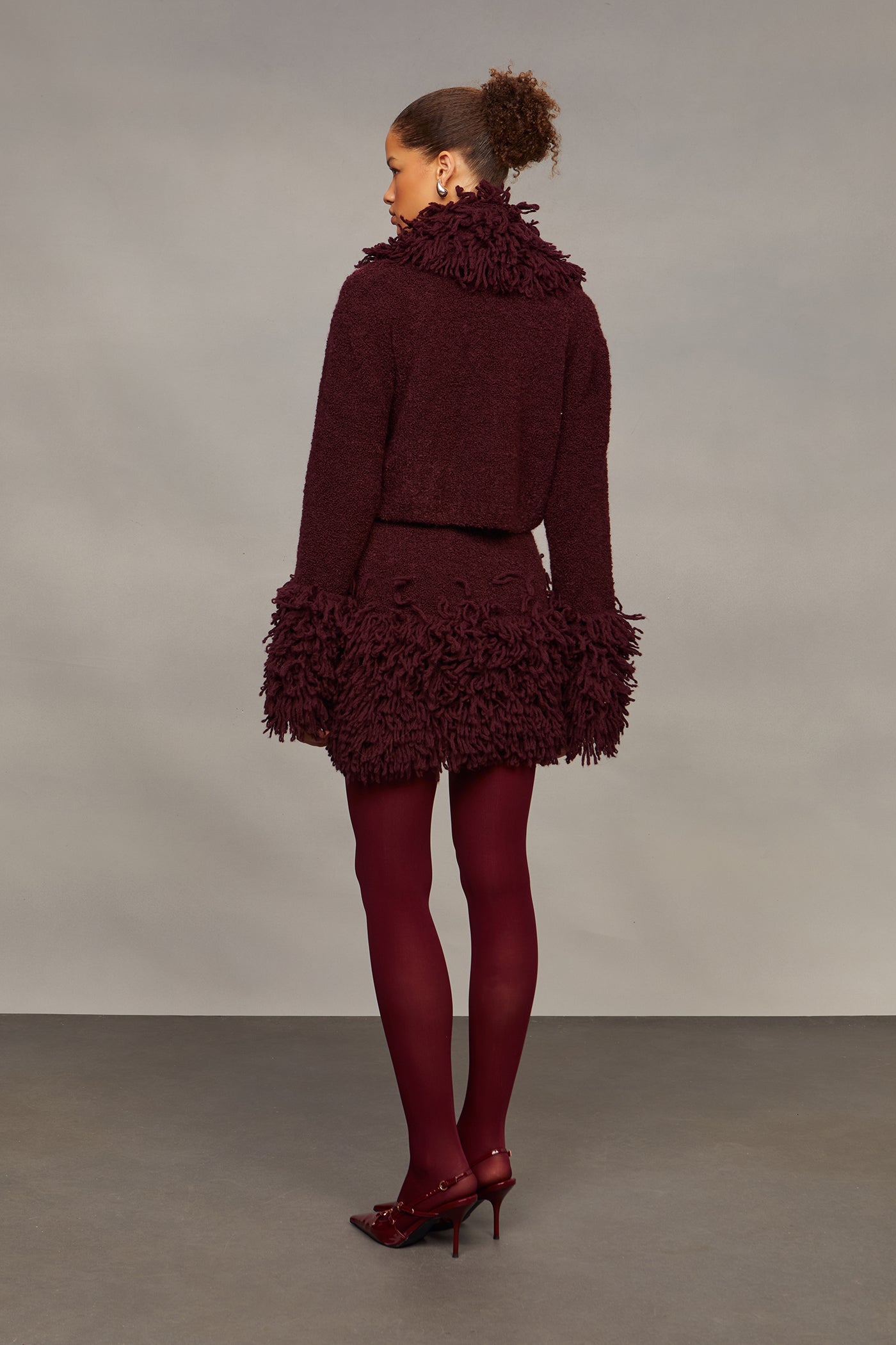 Woman wearing a burgundy textured outfit against a plain background