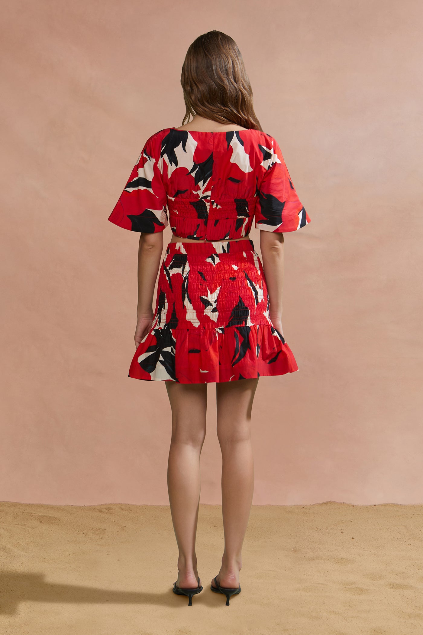 Woman wearing a red floral dress against a beige background