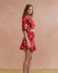 Woman wearing a red and black patterned outfit against a beige background