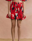Person wearing a red patterned skirt against a beige background