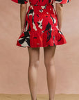 Person wearing a red dress with black and white floral pattern on a beige background