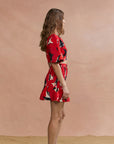 Woman wearing a red floral dress against a pink background