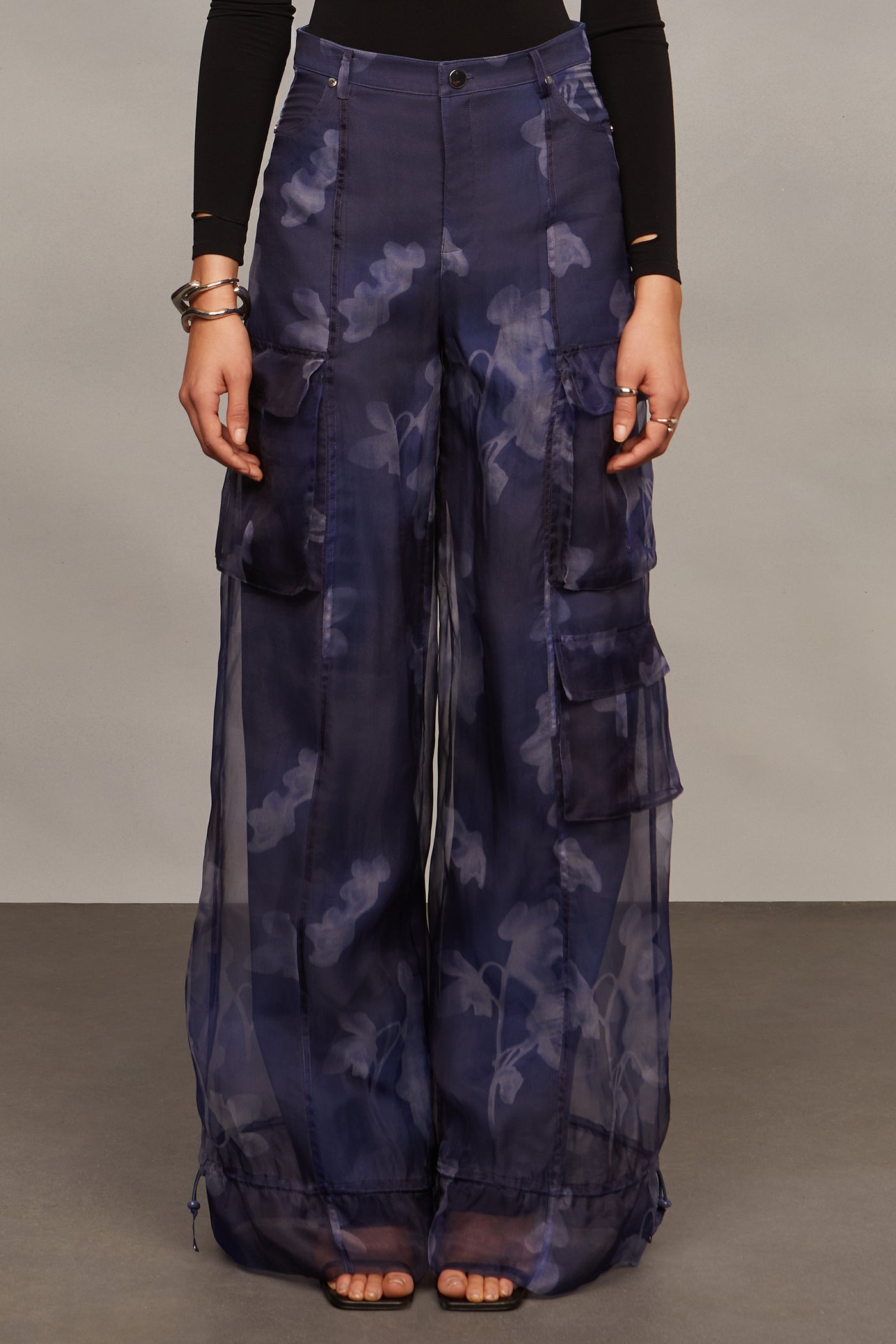Person wearing a pair of dark blue patterned cargo pants on a plain background
