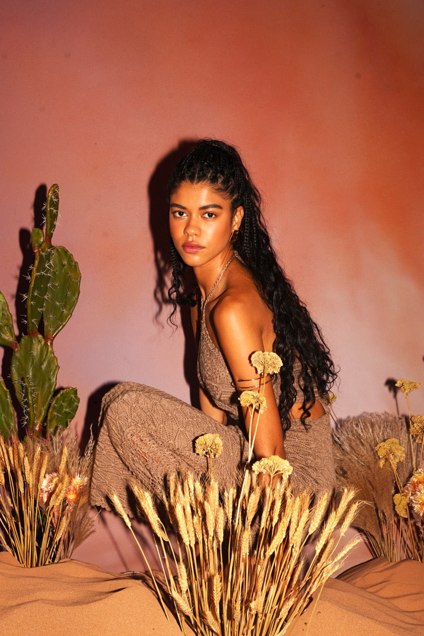Woman sitting among cacti and dried plants with a warm-toned background