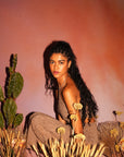 Woman sitting among cacti and dried plants with a warm-toned background