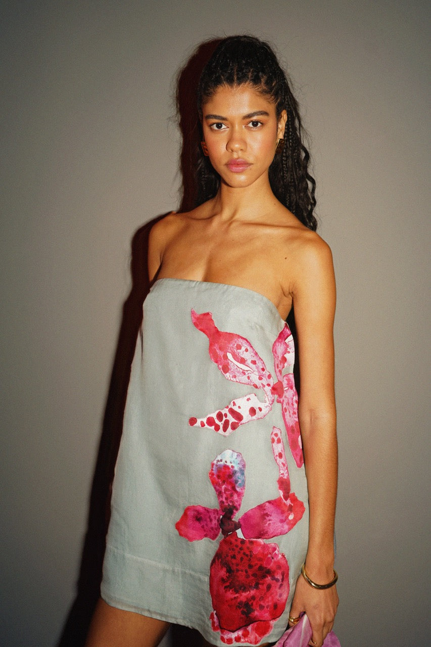 Woman wearing a strapless dress with floral design against a plain background