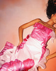 Woman wearing a pink and white dress against a peach background