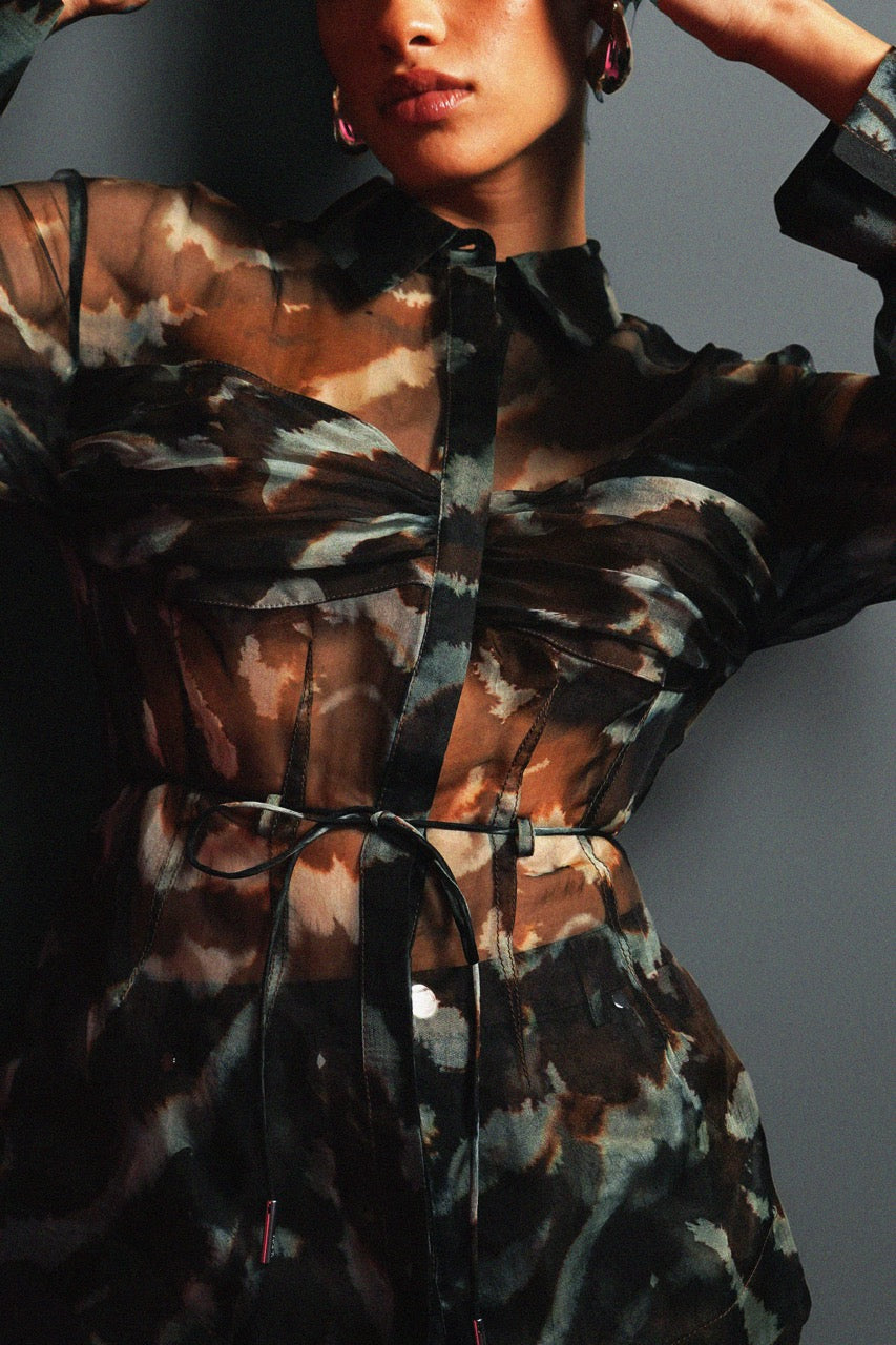 Person wearing a camouflage-patterned outfit with a gray background