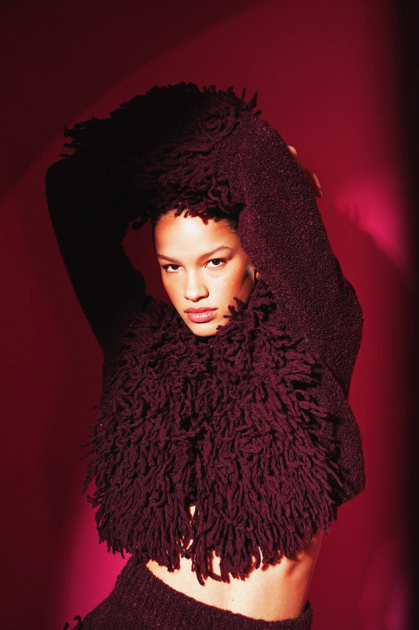 Person wearing a burgundy textured garment against a red background