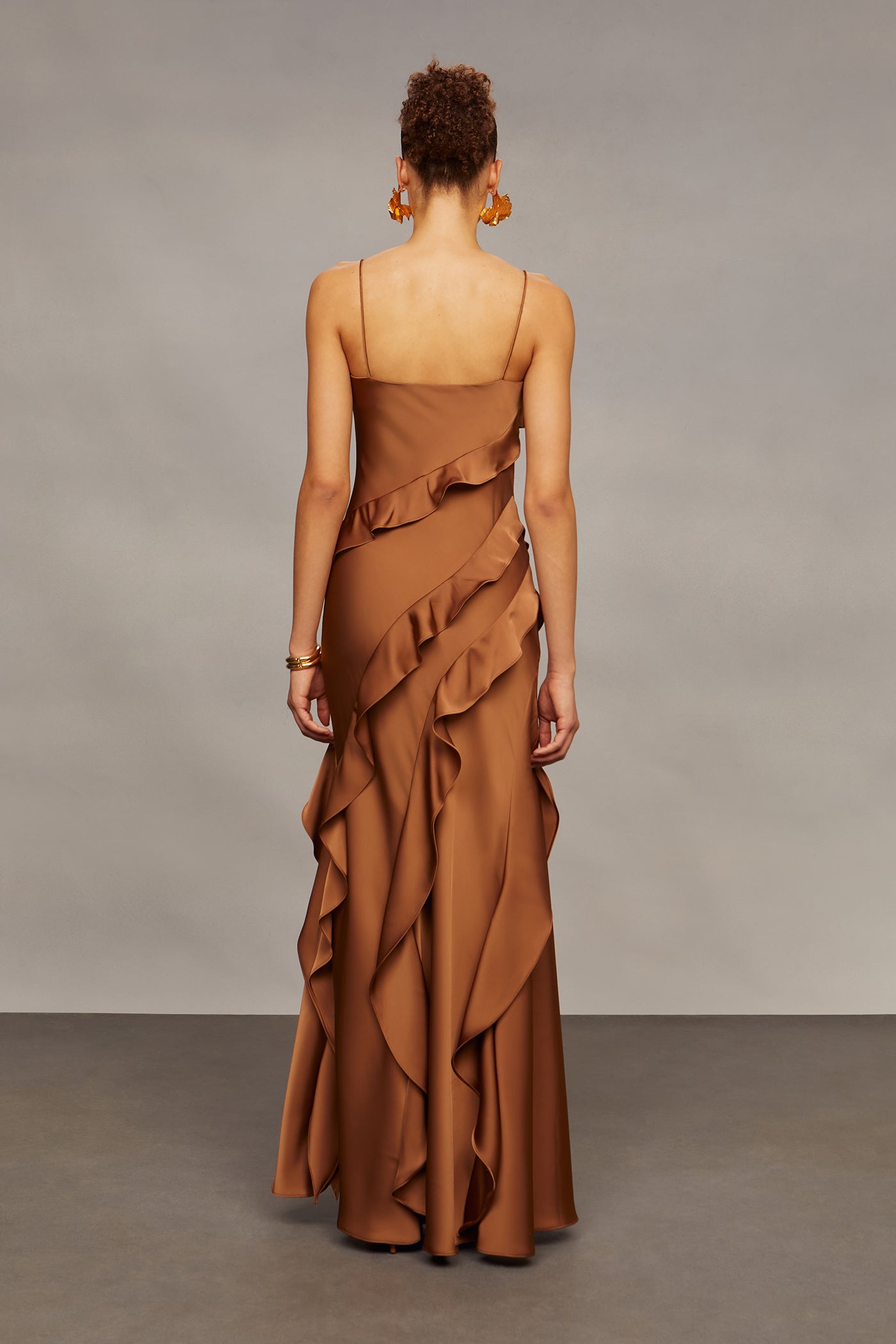 Woman wearing a brown ruffled dress against a neutral background