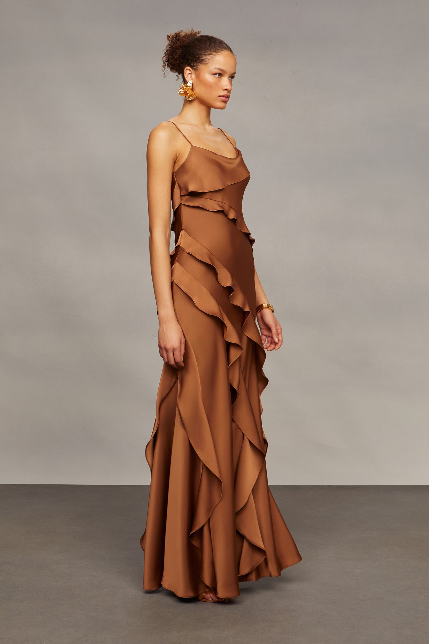 Woman wearing a brown ruffled dress against a gray background
