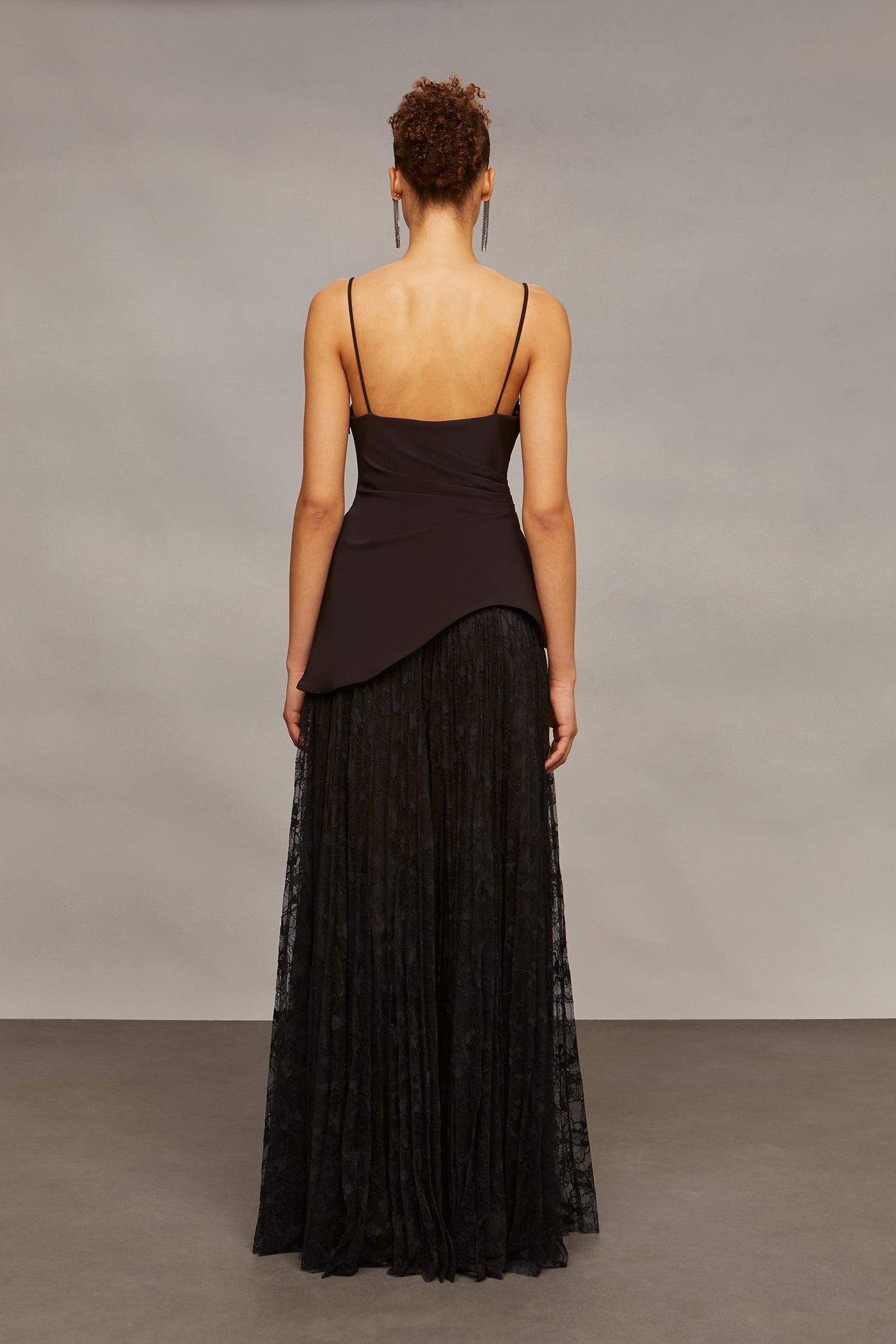 Woman wearing a black dress with a sheer overlay against a plain background