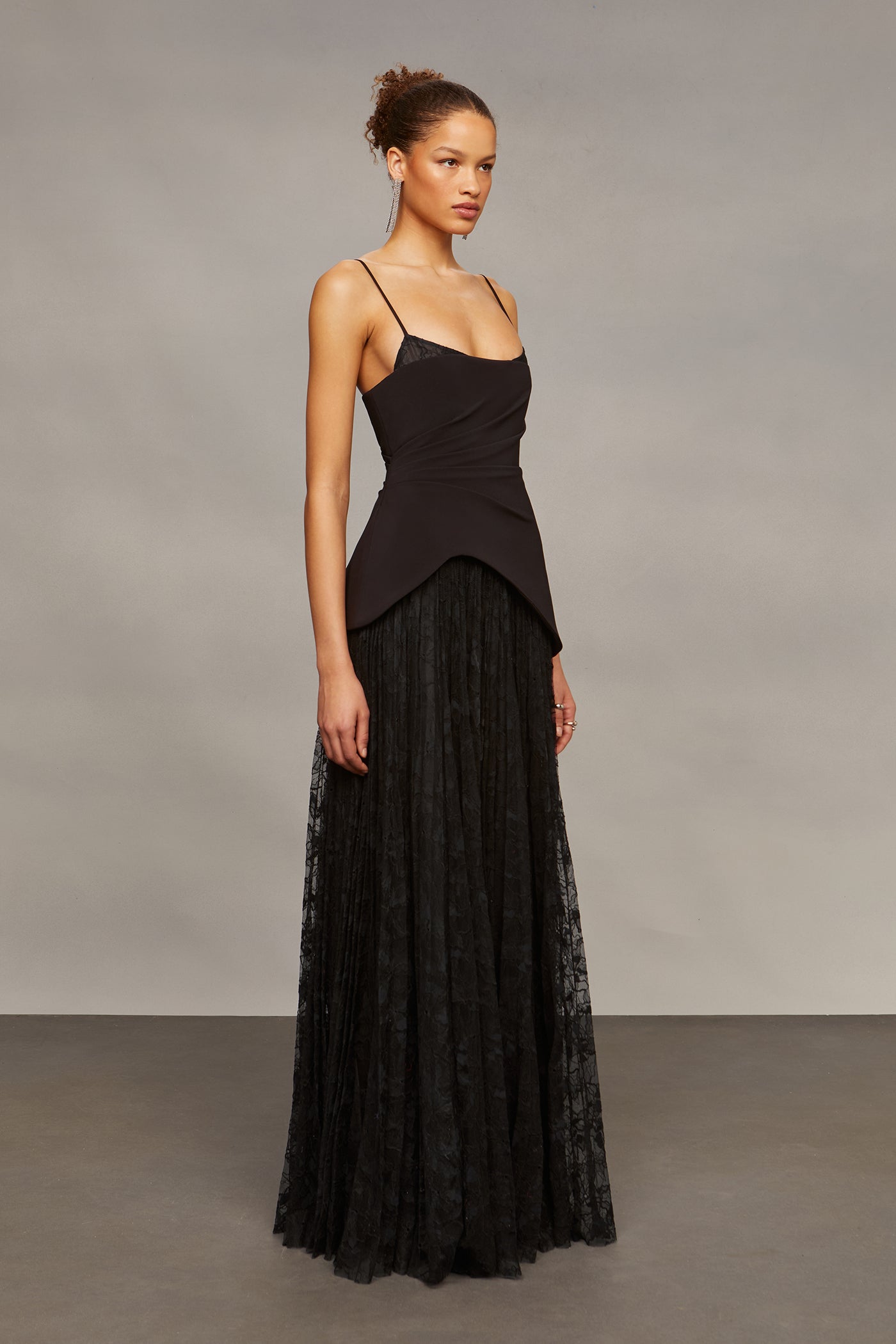 Woman wearing a black dress with a sheer overlay against a neutral background