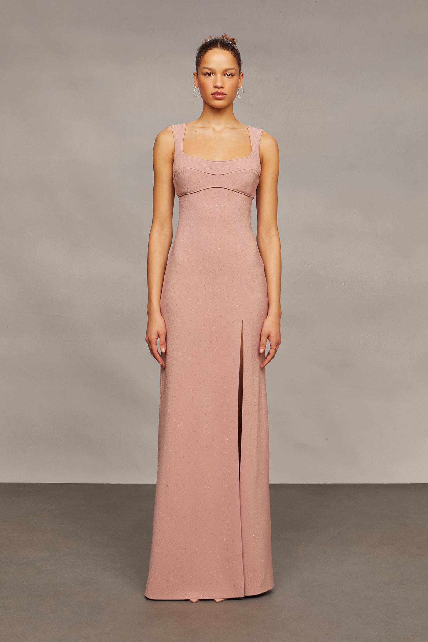 Woman wearing a long pink dress against a plain background