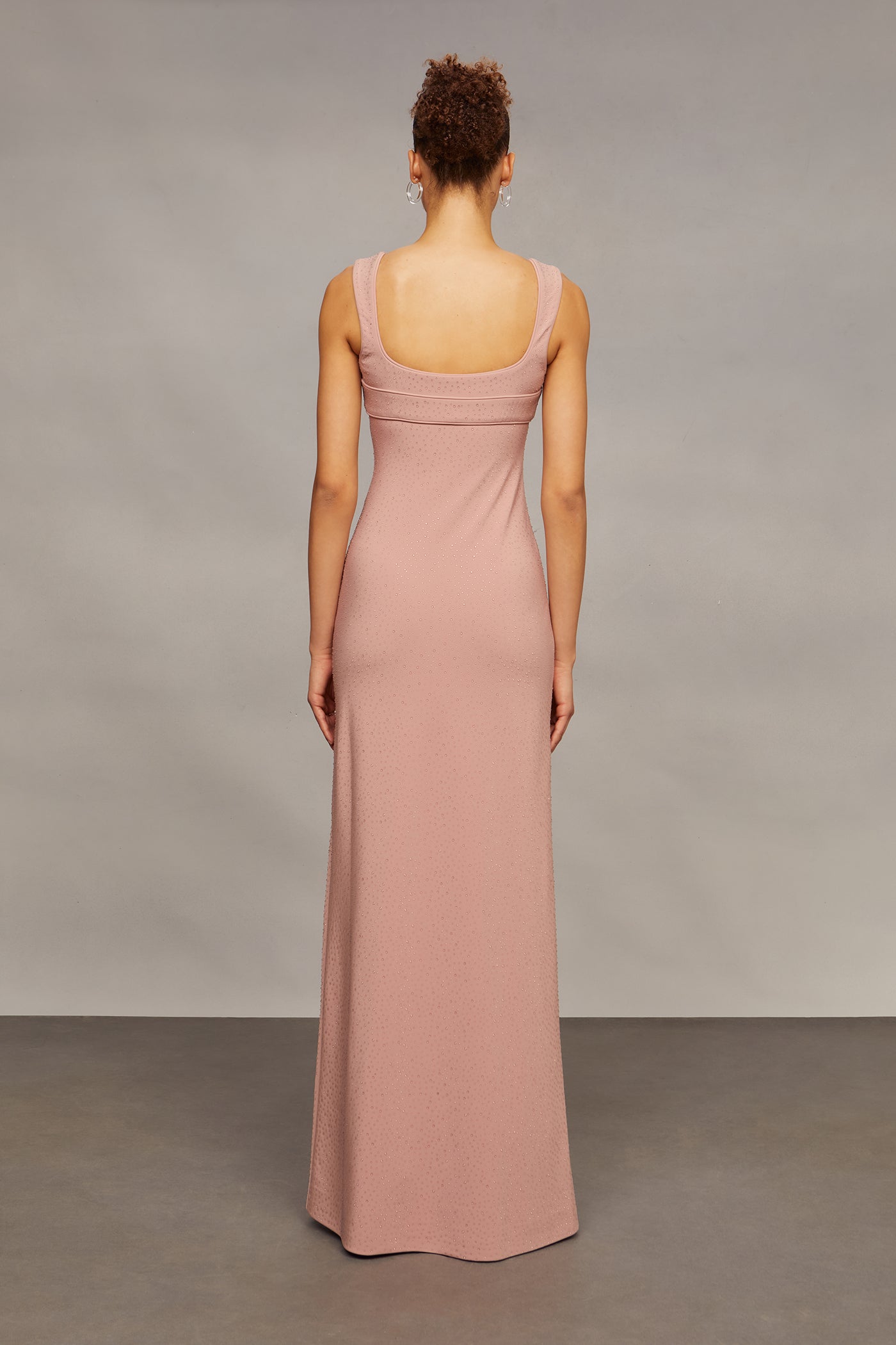 Woman wearing a long pink dress against a plain background