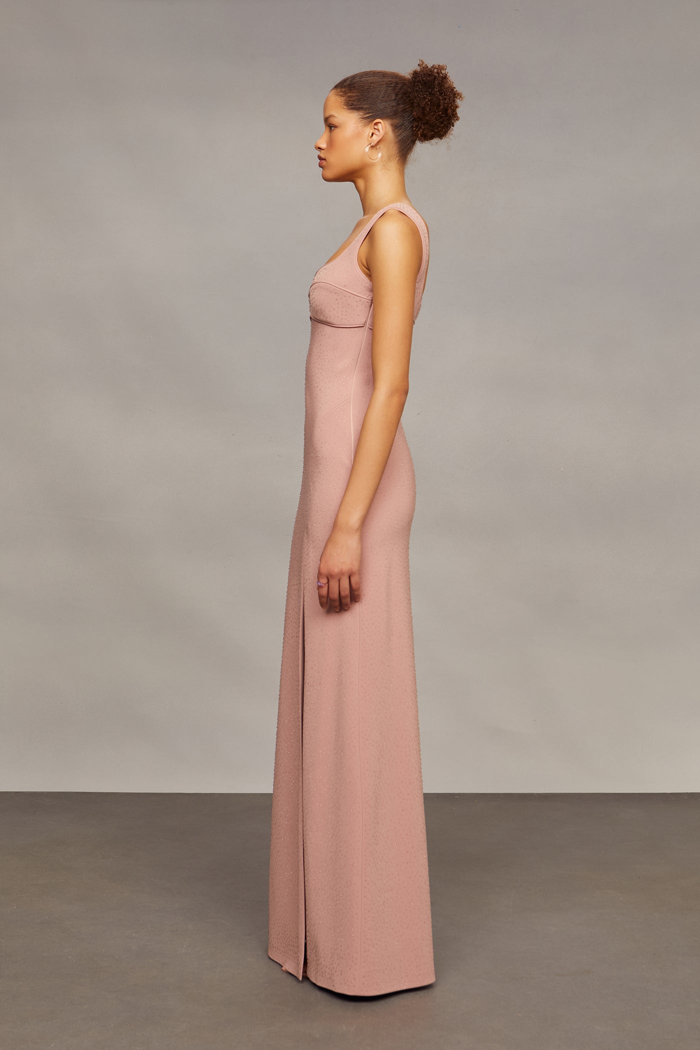 Woman wearing a pink dress standing against a plain background