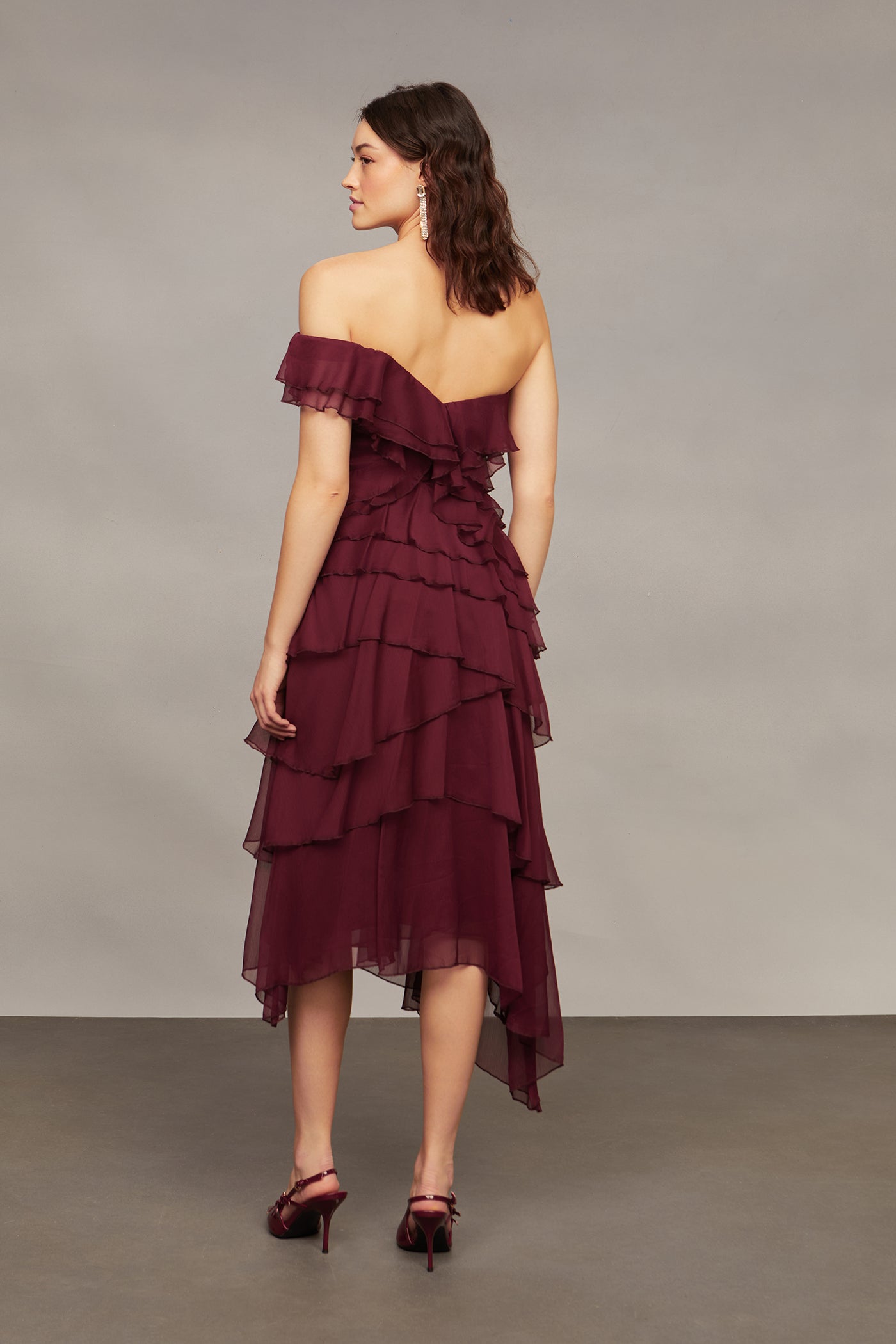 Woman wearing a burgundy off-shoulder dress against a neutral background