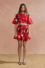 Woman wearing a red floral outfit against a beige background