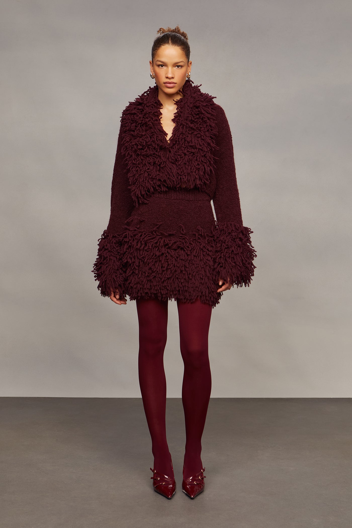 Woman wearing a burgundy textured outfit against a plain background