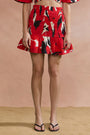 Person wearing a red patterned skirt against a beige background